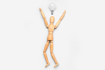 Wooden mannequin with light bulb on light background. Insight concept