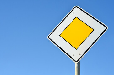 Main road sign against blue sky, closeup