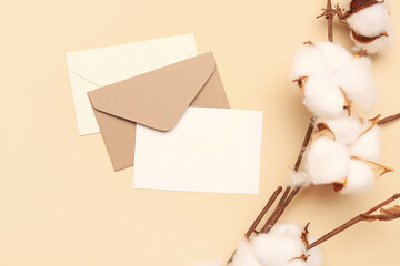 Composition with blank card, envelopes and cotton branch on color background