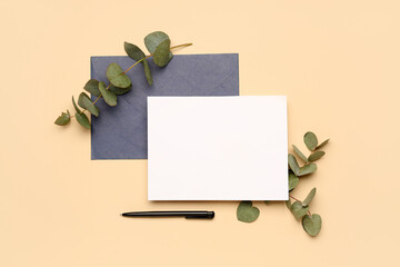 Composition with blank card, envelope, pen and eucalyptus branches on color background