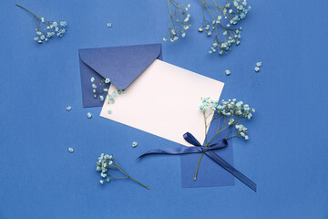 Composition with blank card, envelope and beautiful gypsophila flowers on blue background