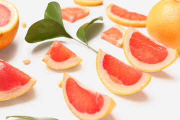 Fototapeta na wymiar Composition with pieces of ripe grapefruit, seeds and plant leaves on white background, closeup
