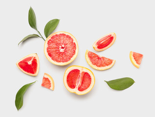 Composition with pieces of juicy grapefruit and plant leaves on white background