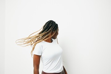 Portrait african american woman in white t-shirt smiling dancing with afro pigtails smile, flying hair, white background. Soft warm colors.