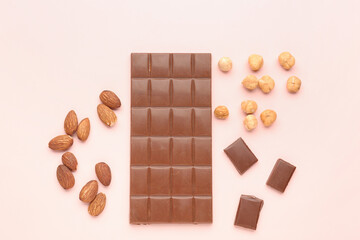 Composition with tasty chocolate and nuts on color background