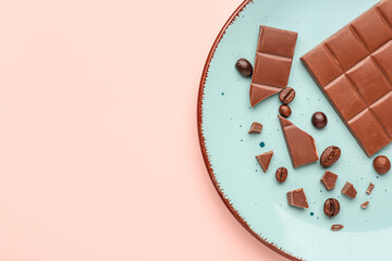 Plate with pieces of tasty chocolate and coffee beans on color background, closeup