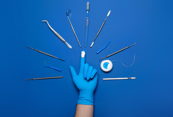 Dentist in medical glove with tools on blue background