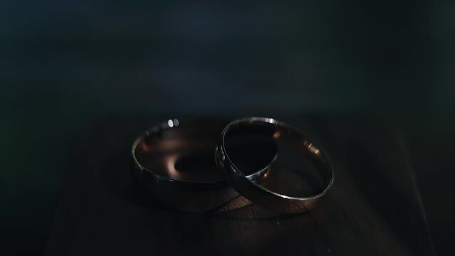 Dynamic light illuminates two gold rings lying on the table. Shooting rings in close-up
