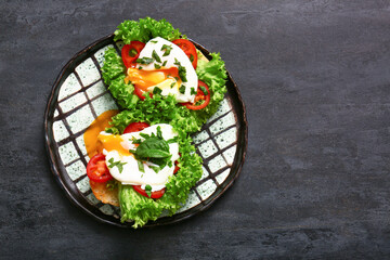 Plate with tasty eggs Benedict on black grunge table