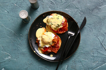 Plate with tasty eggs Benedict on grey grunge table
