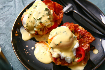 Plate with tasty eggs Benedict on grey grunge table, closeup