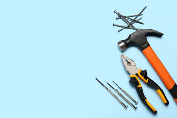 Pliers, hammer and nails on blue background