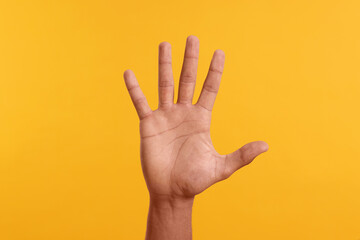 Man giving high five on yellow background, closeup of hand - obrazy, fototapety, plakaty
