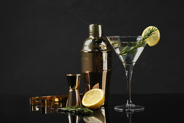 Martini cocktail with lemon slice, rosemary, shaker and fresh fruit on black background