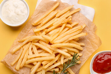 Board with tasty french fries, mayonnaise and ketchup on yellow background