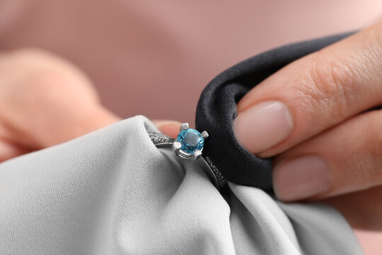 Jeweler cleaning topaz ring with microfiber cloth, closeup
