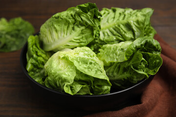 Bowl of fresh green romaine lettuces on wooden table, closeup