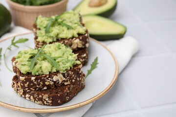 Delicious sandwiches with guacamole and arugula on white table, closeup