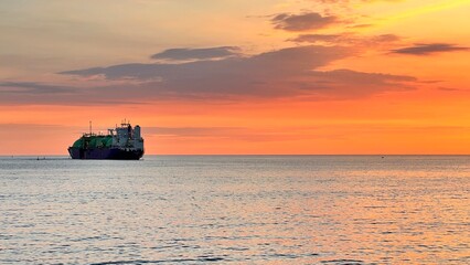 Obraz premium beautiful sunset with ship to the horizon. golden hour at sea
