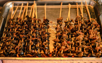 Deep-fried sea mussels glazed in syrup skewered on sticks for sale at Nongmon Market, Bangsaen, Thailand.