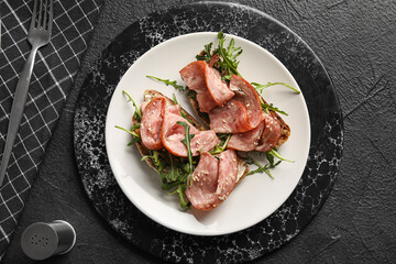 Plate of tasty bruschettas with ham on black background
