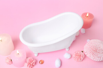 Fototapeta na wymiar Small bathtub, burning candles, sponge, cotton balls and carnation flowers on color background