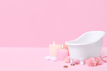 Fototapeta na wymiar Small bathtub, burning candles and carnation flowers on color background