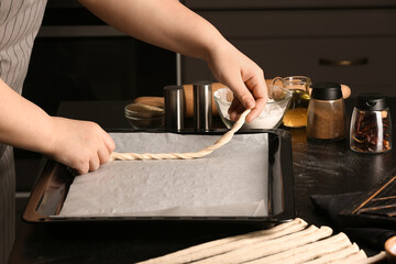Woman preparing Italian Grissini at table in kitchen, closeup