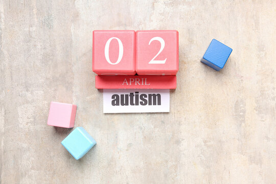 Date 2 APRIL with word AUTISM and cubes on grunge background