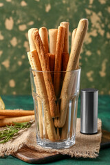 Glass with tasty Italian Grissini on table