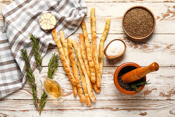Composition with tasty Italian Grissini, rosemary, sauce and spices in light wooden background