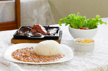 prepared dish, rice, beans, farofa, meat, sausage and salad on a table.