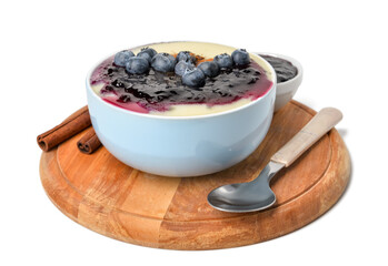 Bowl of tasty semolina porridge with blueberry jam and cinnamon on white background