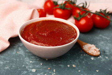 Bowl with tasty tomato paste, salt and fresh vegetables on grey grunge background