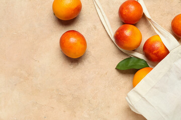 Eco bag with scattered tasty blood orange fruits on beige background