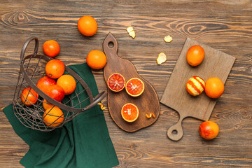 Metal basket and boards with tasty blood oranges on wooden background