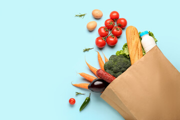 Paper bag with vegetables, bread and milk on light blue background