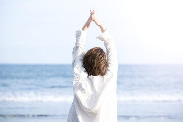 砂浜で深呼吸やストレッチ伸びをする女性 ストレスフリー