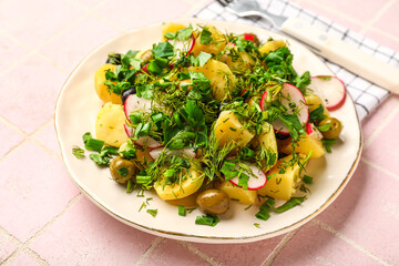 Plate of tasty Potato Salad with vegetables on pink tile background