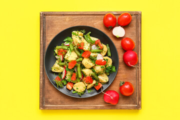 Plate of tasty Potato Salad with vegetables on yellow background