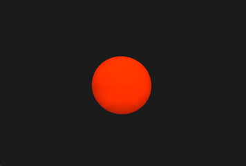  close-up of a large, bright, red circle in the center of a black background. It could be the sun setting or rising.