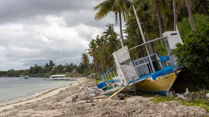 Fototapeta na wymiar a large boat wrecked by a hurricane and storm, on the shore of a tropical island