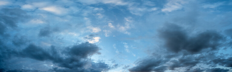 Detailed panorama of bright blue sky with many clouds in shades from pure white to blues and grays.

