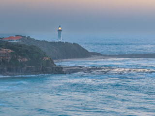 Aerial sunrise seascape with lighthouse, high tide and rock platform