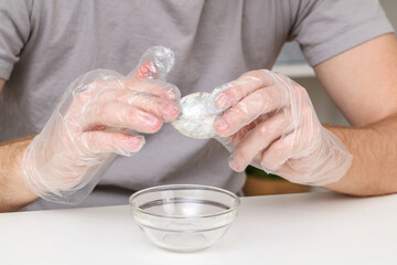 A man puts disposable plastic gloves on his hands to dye Easter eggs. Coloring of Easter eggs.