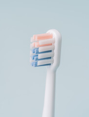 Vertical photo of an electric toothbrush head in profile against blue background.