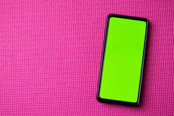 Horizontal view of cell phone with green chroma key in the screen with a pink background and copy...