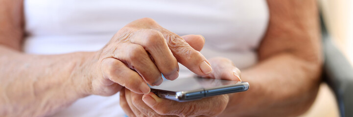 Closeup of hands of elderly woman with smartphone