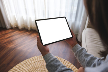 Mockup image of a woman holding digital tablet with blank desktop screen while lying on a sofa at home