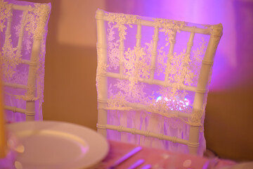 Table setup for a formal dining experience such a wedding or a banquet with focus on a white chair...